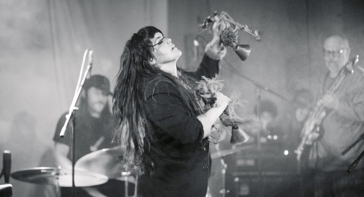 Ibelisse Guardia Ferragutti and Frank Rosaly performing live. A black and white photo shows her lost in music while playing percussion