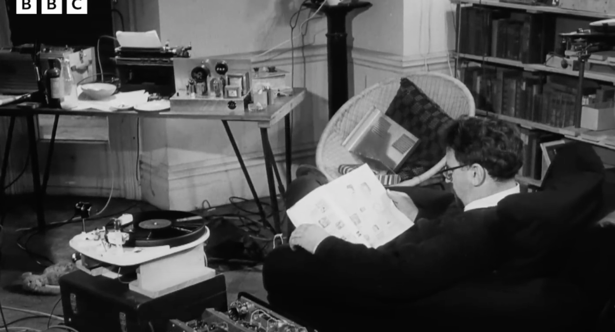 A man reading while listening to his stereo in his living room.