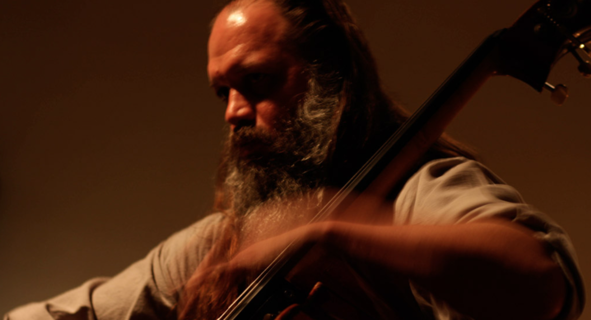Mark Deutsch, with a long beard and long hair, playing his bazantar.