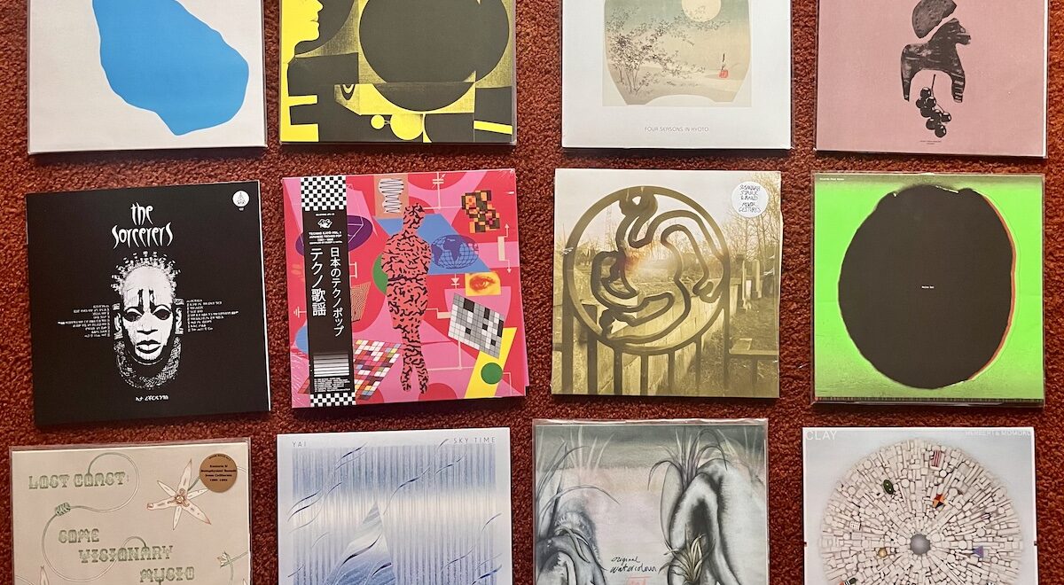 A grid of twelve vinyl record sleeves arranged on a rust-colored carpet, featuring abstract and minimalist artwork in blues, greens, pinks, blacks and neutrals, representing a range of contemporary, experimental, ambient and international music releases.