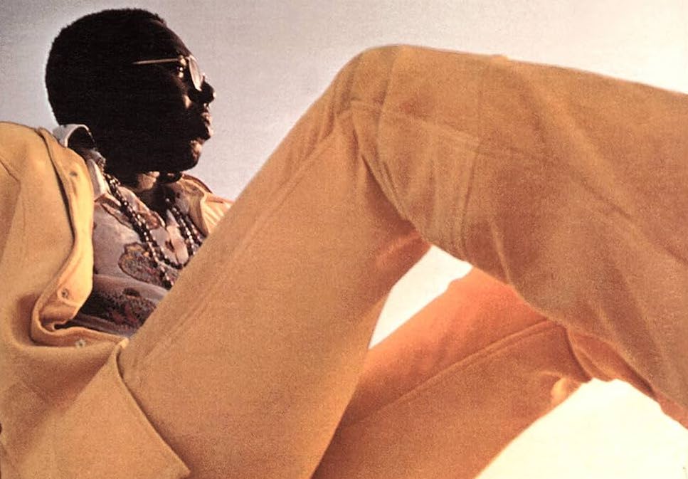 Curtis Mayfield from the cover of “Curtis.” He is sitting down and wearing a yellow suit.