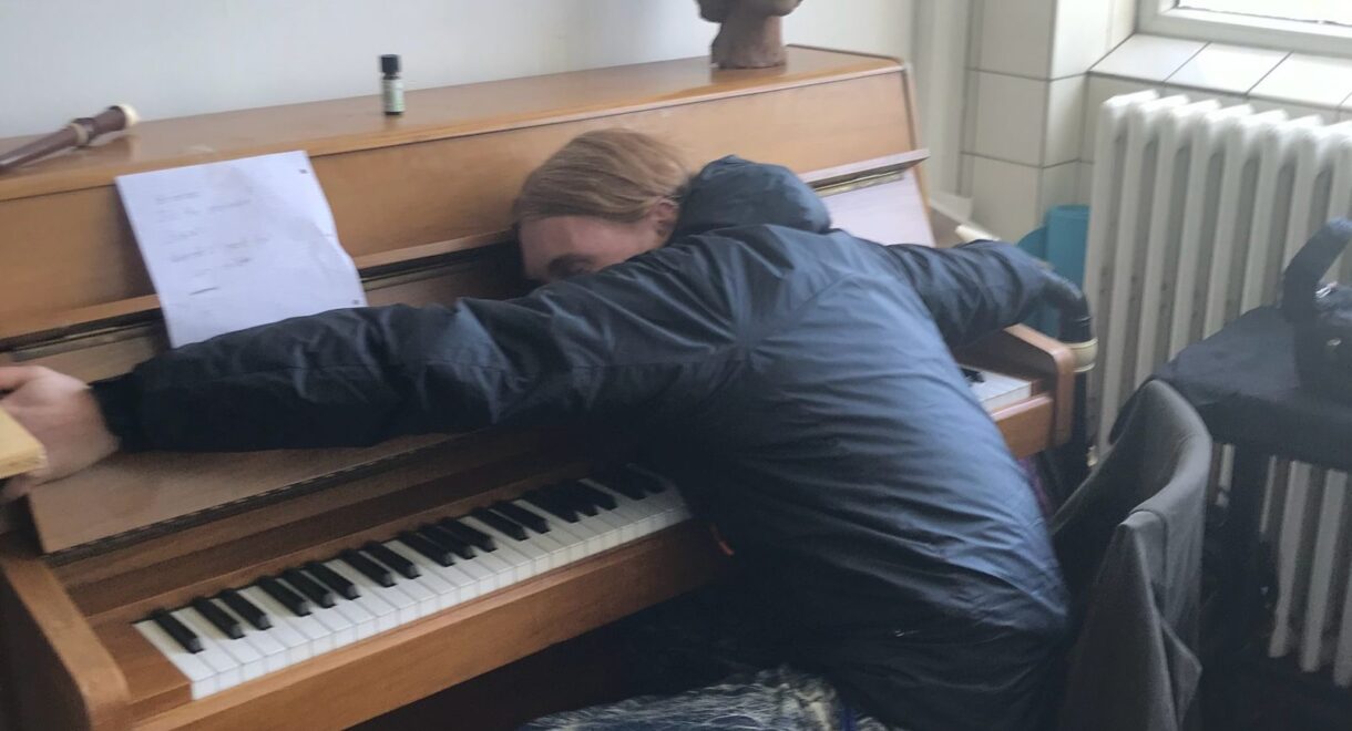 John T. Gast draped over an upright piano like he's asleep.