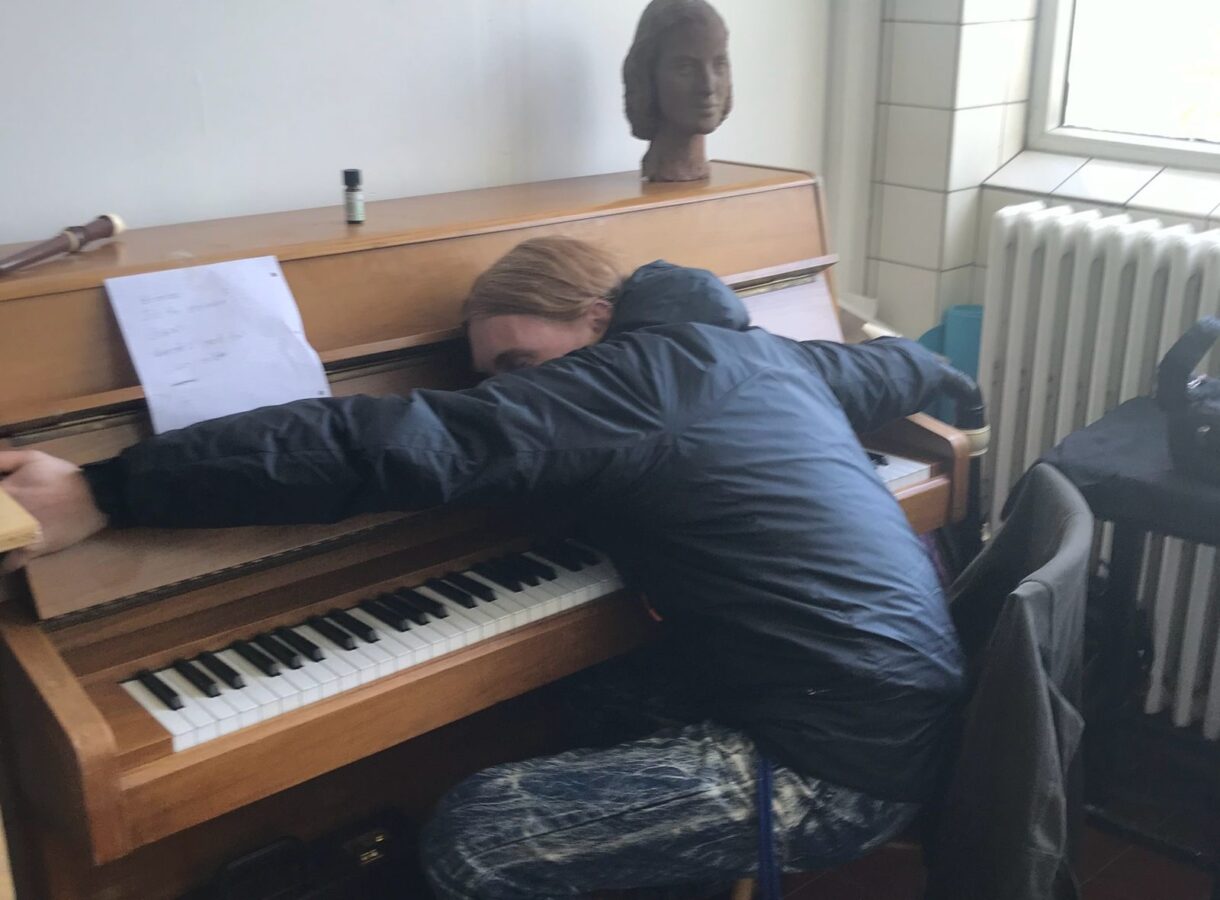 John T. Gast draped over an upright piano like he's asleep.